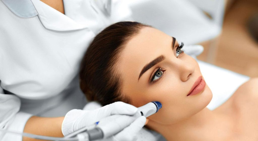 Woman receiving facial skin treatment at spa.